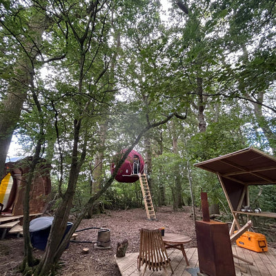 The Strawberry Lane Tree Tent, featuring a red, spherical Tree Tent, kitchenette, bathroom with shower, outdoor tub and pizza oven